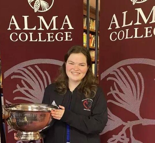 alma college student holding award